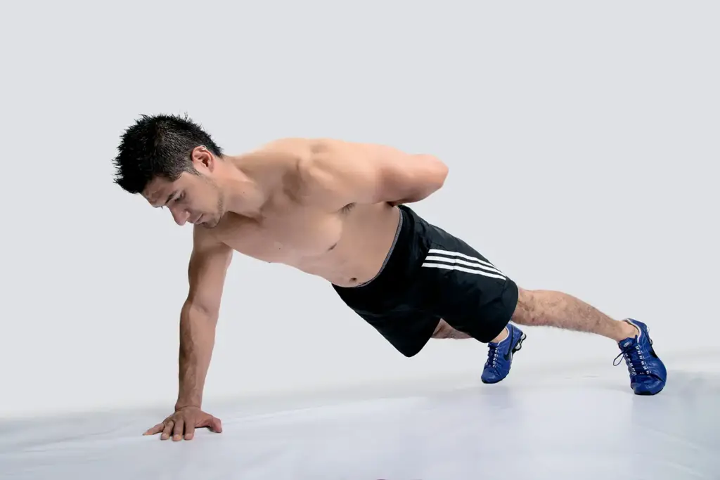 Man performing a side plank exercise in gym attire.